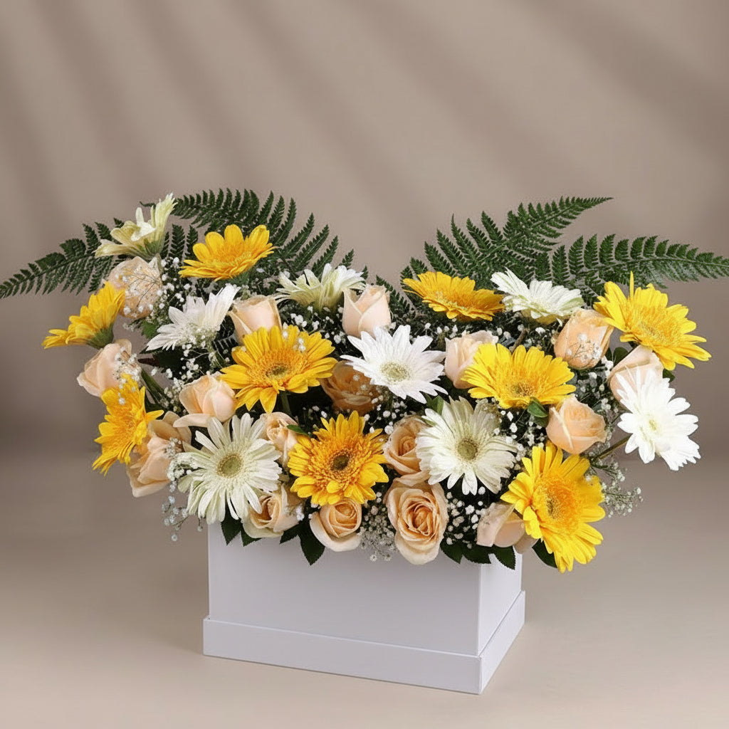 Bouquet of yellow, white, and peach flowers in a black and white striped box on a teal background.
