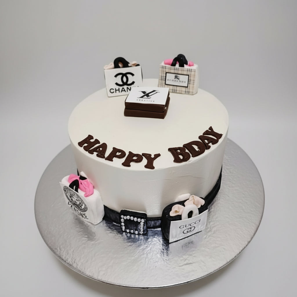White birthday cake with 'Happy Birthday' text, surrounded by luxury brand packaging on a marble background.