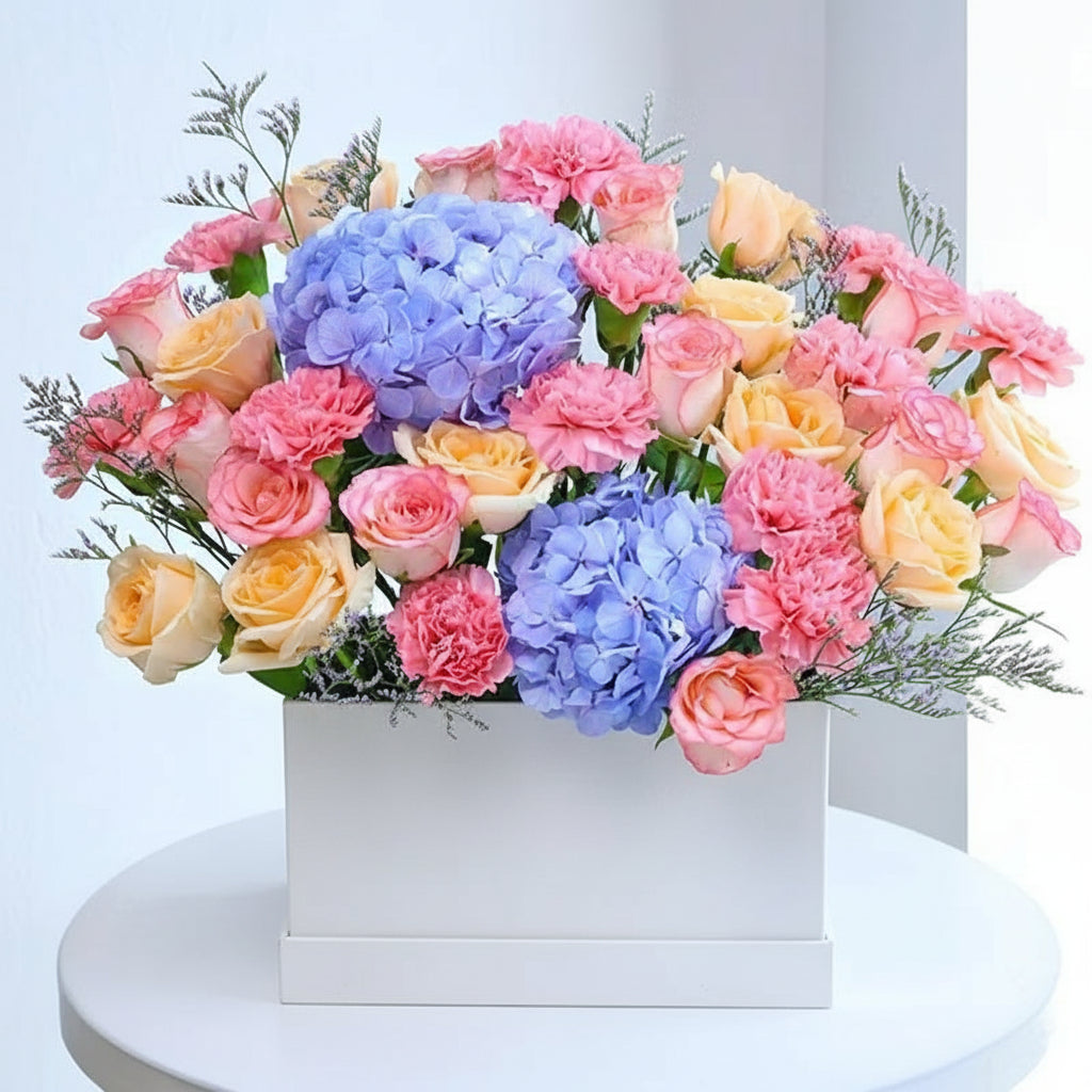 Bouquet of colorful flowers in a striped box with  branding on a white background.

