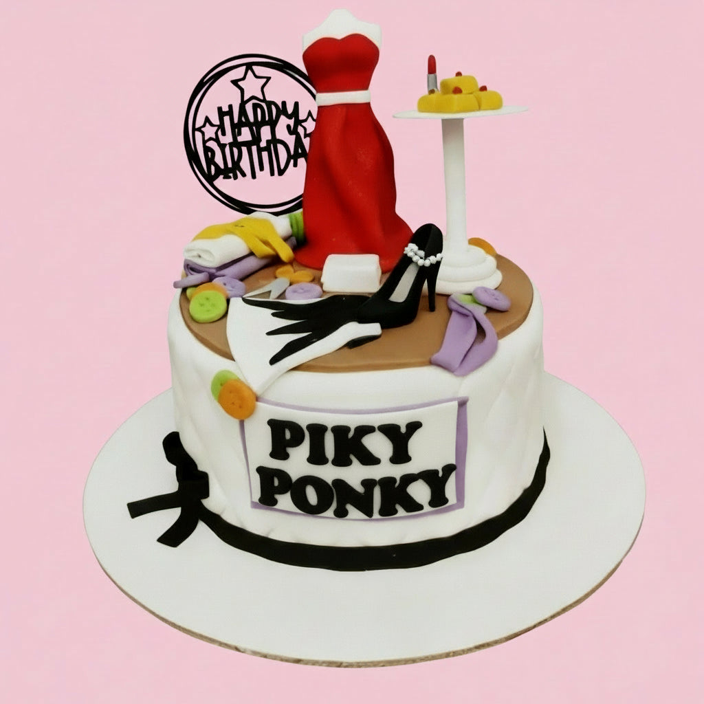 Two-tier birthday cake with 'Happy Birthday' topper, red dress, and other items on a white background.